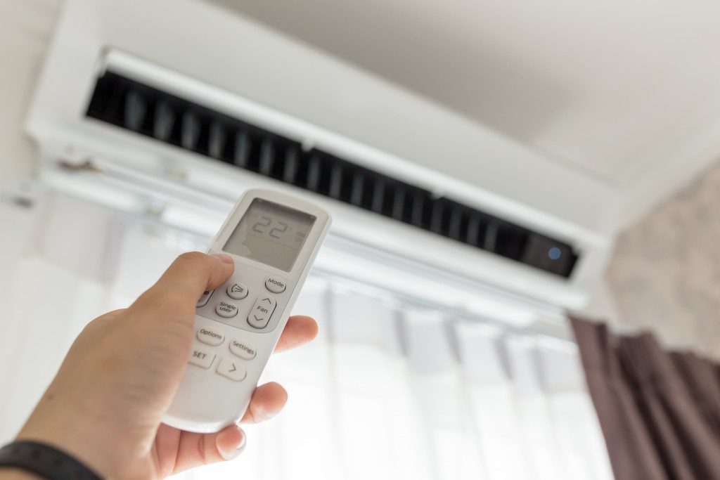 person pointing remote controller to aircon