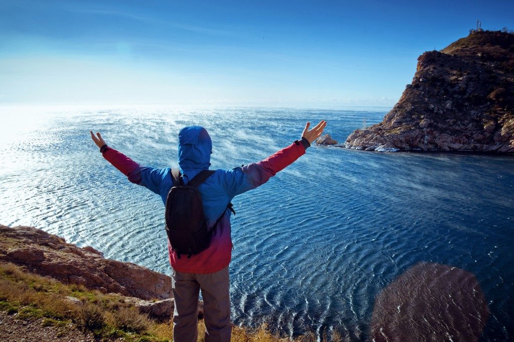 Man standing on a mountain with his arms raised