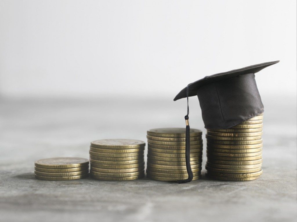 stacked coins and a graduation cap