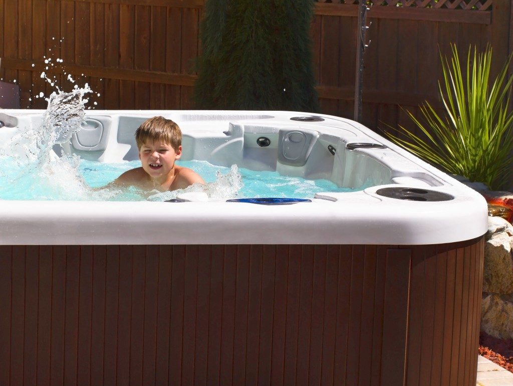 Happy boy playing with bubbles in hot tube on the back yard