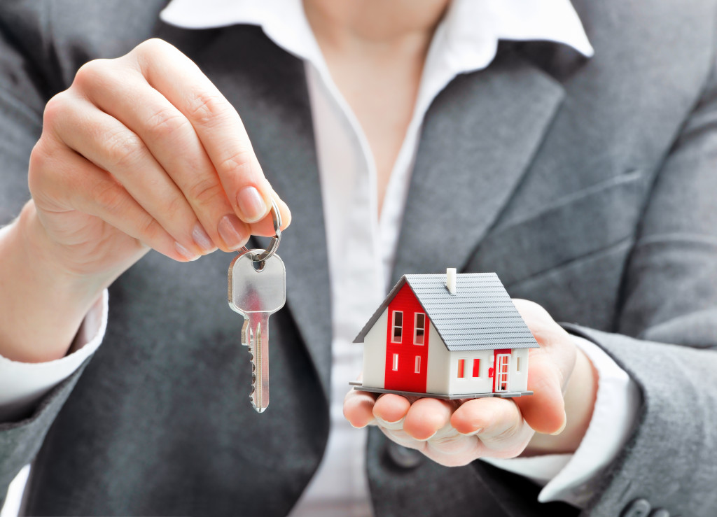 a person holding a key and a cardboard replica of a house