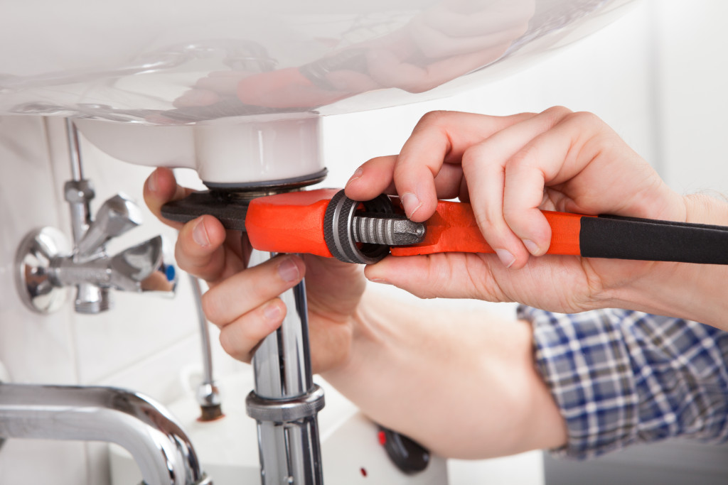 a close up of a man using a wrench to fix bathroom sink