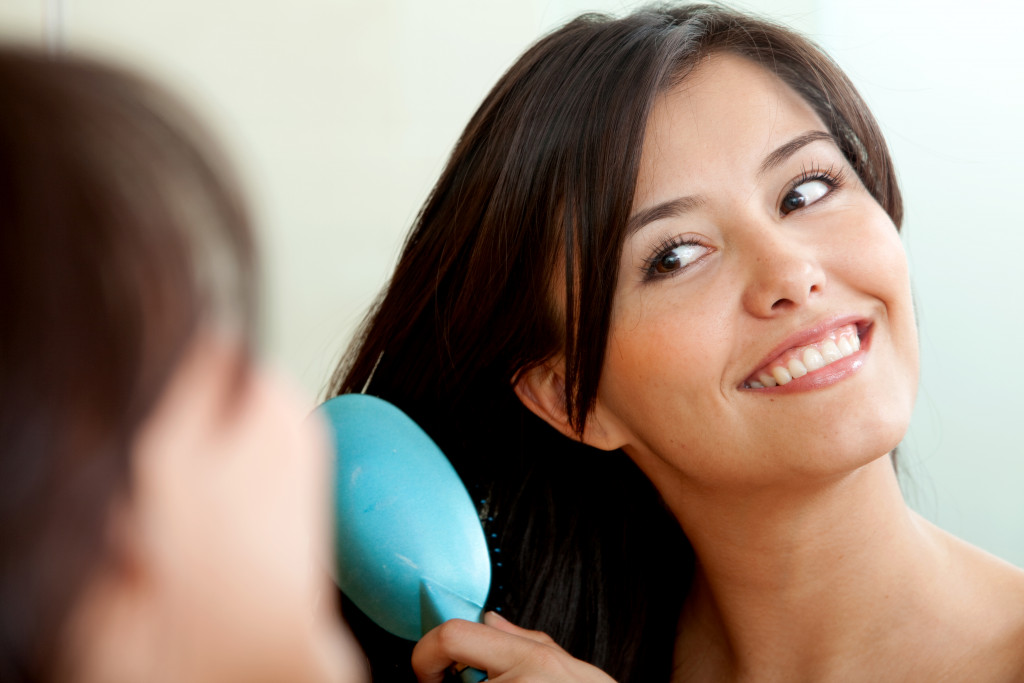 a young woman brushing gorgeous locks in front of a mirror