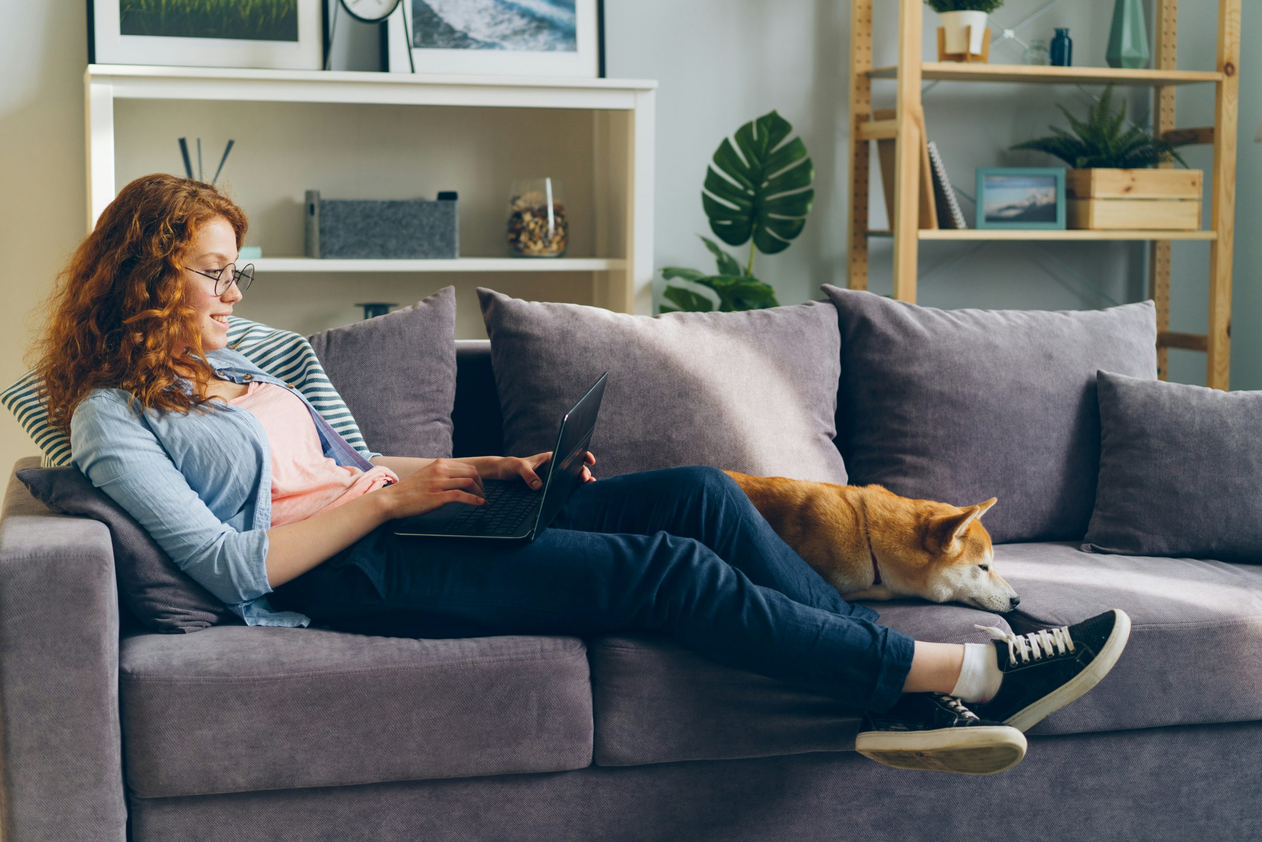 woman working on her laptop, with her dog beside her